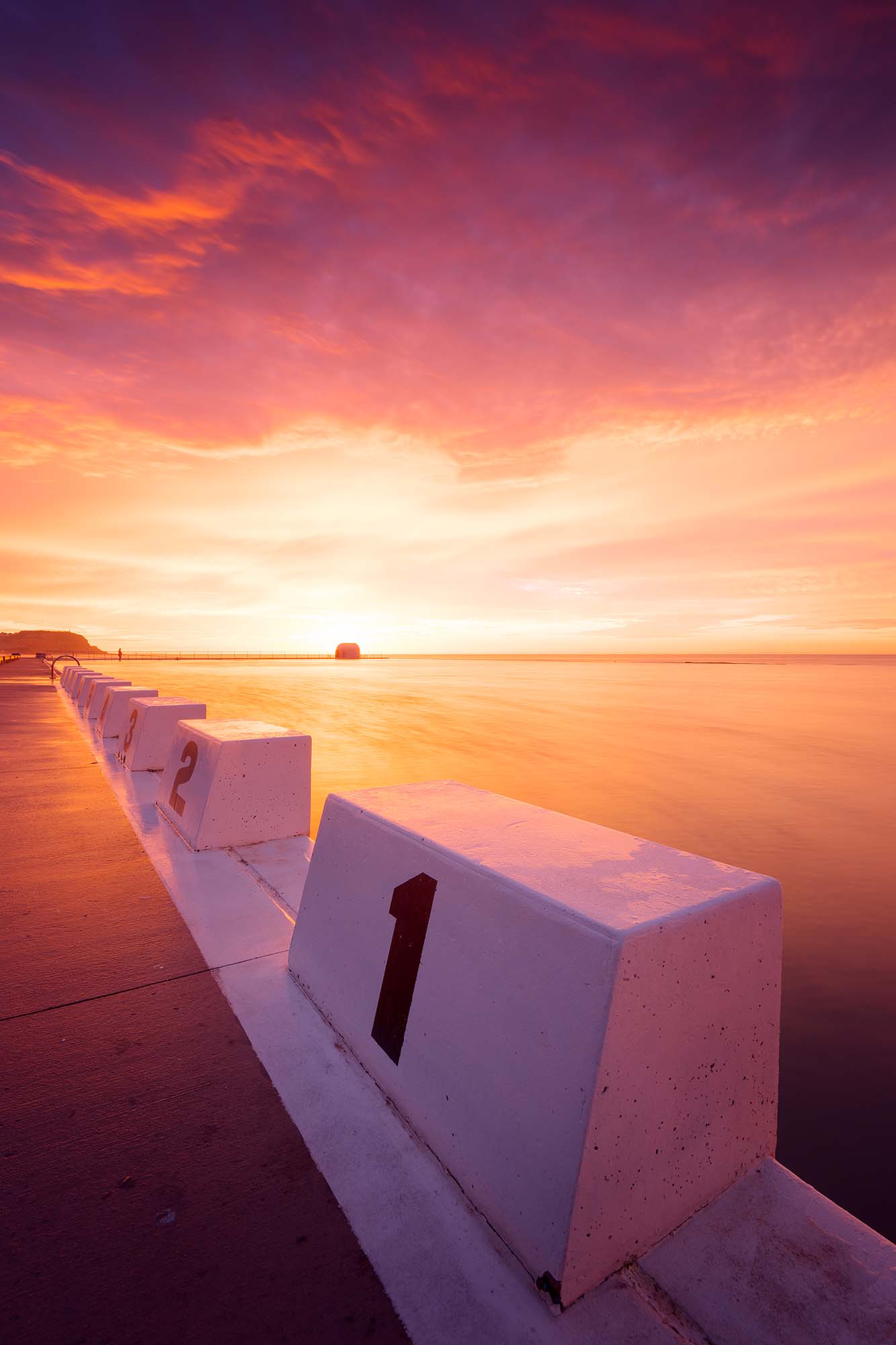 Portrait sunrise at Merewether Ocean Baths with concrete blocks leading toward the ocean, Newcastle NSW