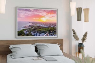Framed wall art featuring a golden sunset over ANZAC Memorial Walk displayed above a bed in a modern bedroom.