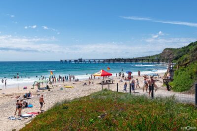Catherine Hill Bay Beach on a sunny summer day with golden sand, clear blue water, and coastal scenery in New South Wales.