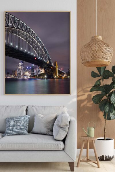 Photograph of the Sydney Harbour Bridge illuminated at night with city skyline and harbour reflections.