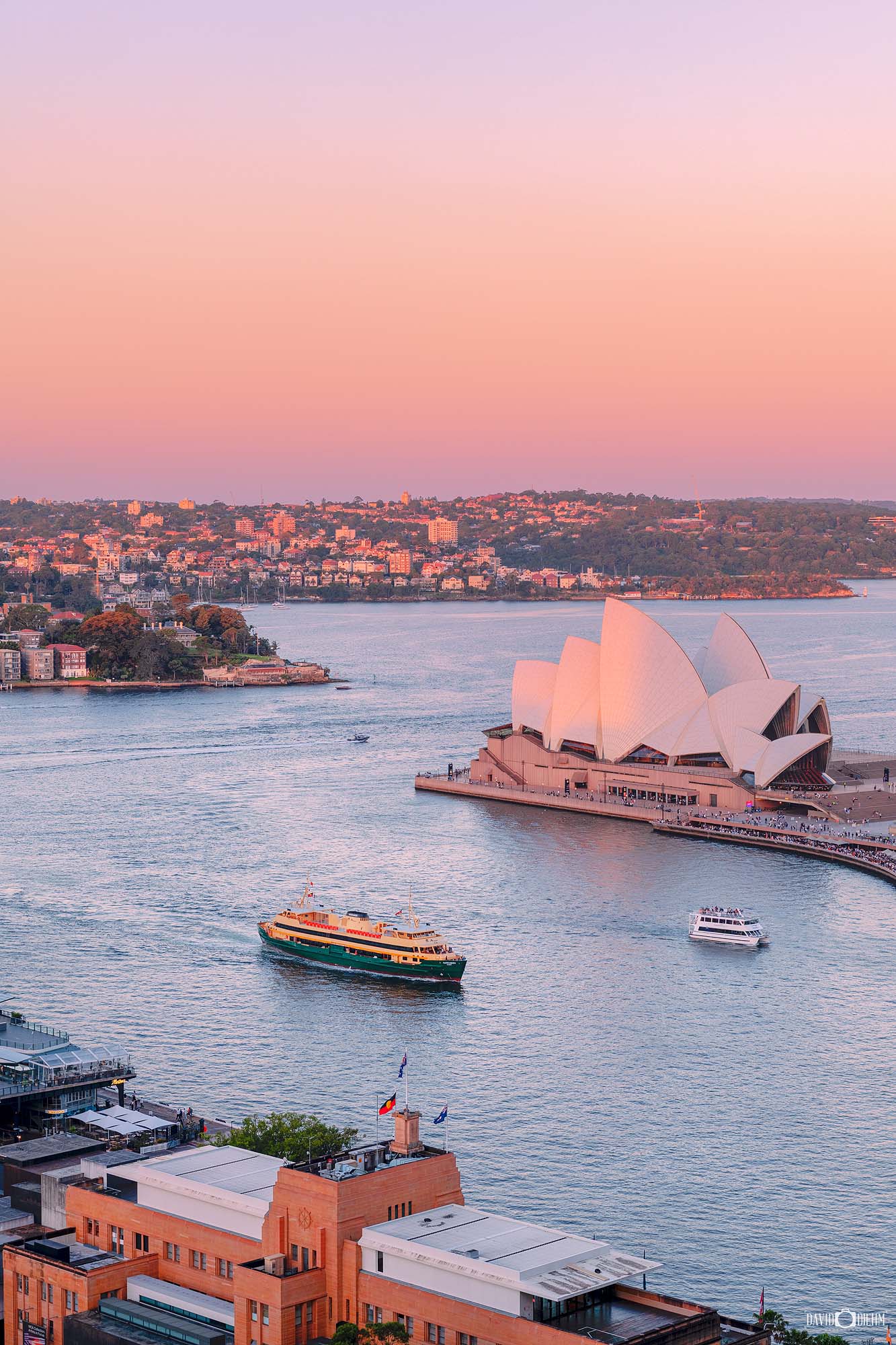 Sydney Opera House at sunset with warm golden light reflecting across Sydney Harbour and highlighting its iconic sail-like structure.