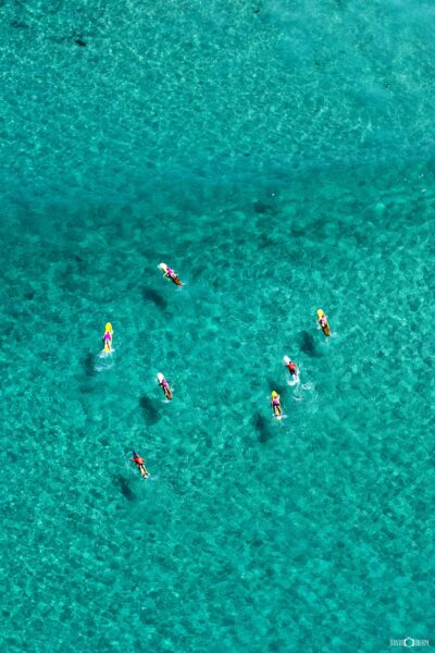 Aerial photograph of surfboards and surfers in turquoise water at Bondi Beach in Sydney, captured from above.