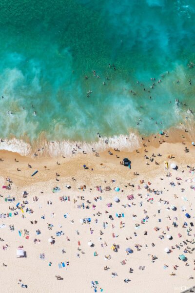 Aerial photograph of people enjoying Bondi Beach in Sydney, showing beach activity, swimmers, and surfers from above.