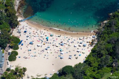 Aerial photograph of Shelly Beach in Manly, Sydney, showing the calm bay, turquoise water, and surrounding coastal landscape.