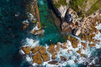 Aerial photograph of Giles Baths in Coogee, Sydney, showing the ocean rock pool and surrounding rocky coastline from above.