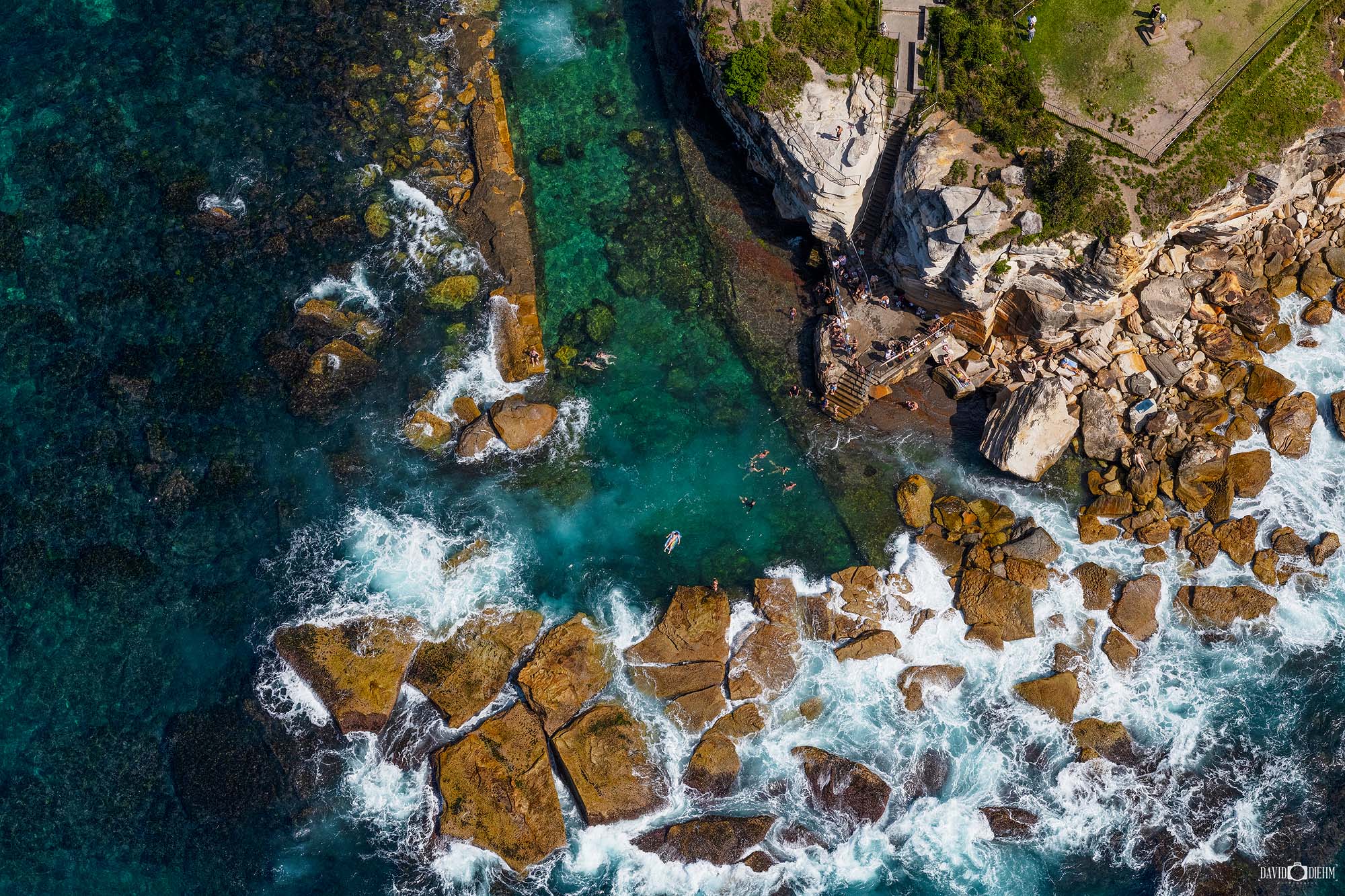 Aerial photograph of Giles Baths in Coogee, Sydney, showing the ocean rock pool and surrounding rocky coastline from above.