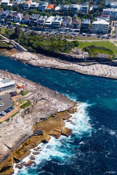 Aerial photograph of the rock platform at Clovelly Beach in Sydney, Australia, showing textured sandstone, ocean edge, and coastal formations from above.