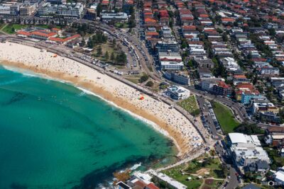 Aerial photograph of North Bondi Beach in Sydney, Australia, showing the coastal reserve, beach curve, and surrounding neighbourhood from above.