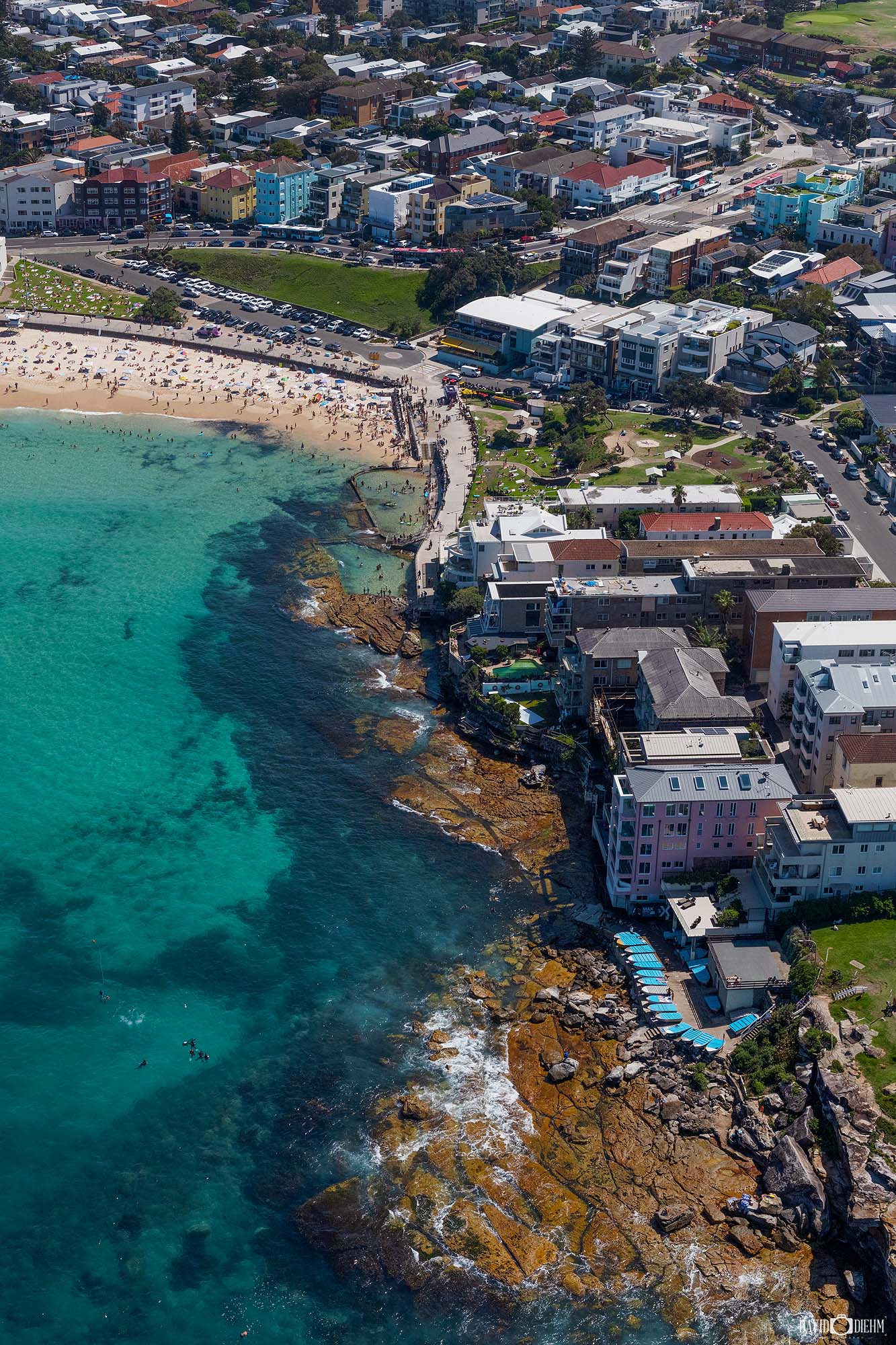 Aerial photograph of North Bondi Beach in Sydney, Australia, showing the shoreline, surf, and surrounding coastal reserve from above.