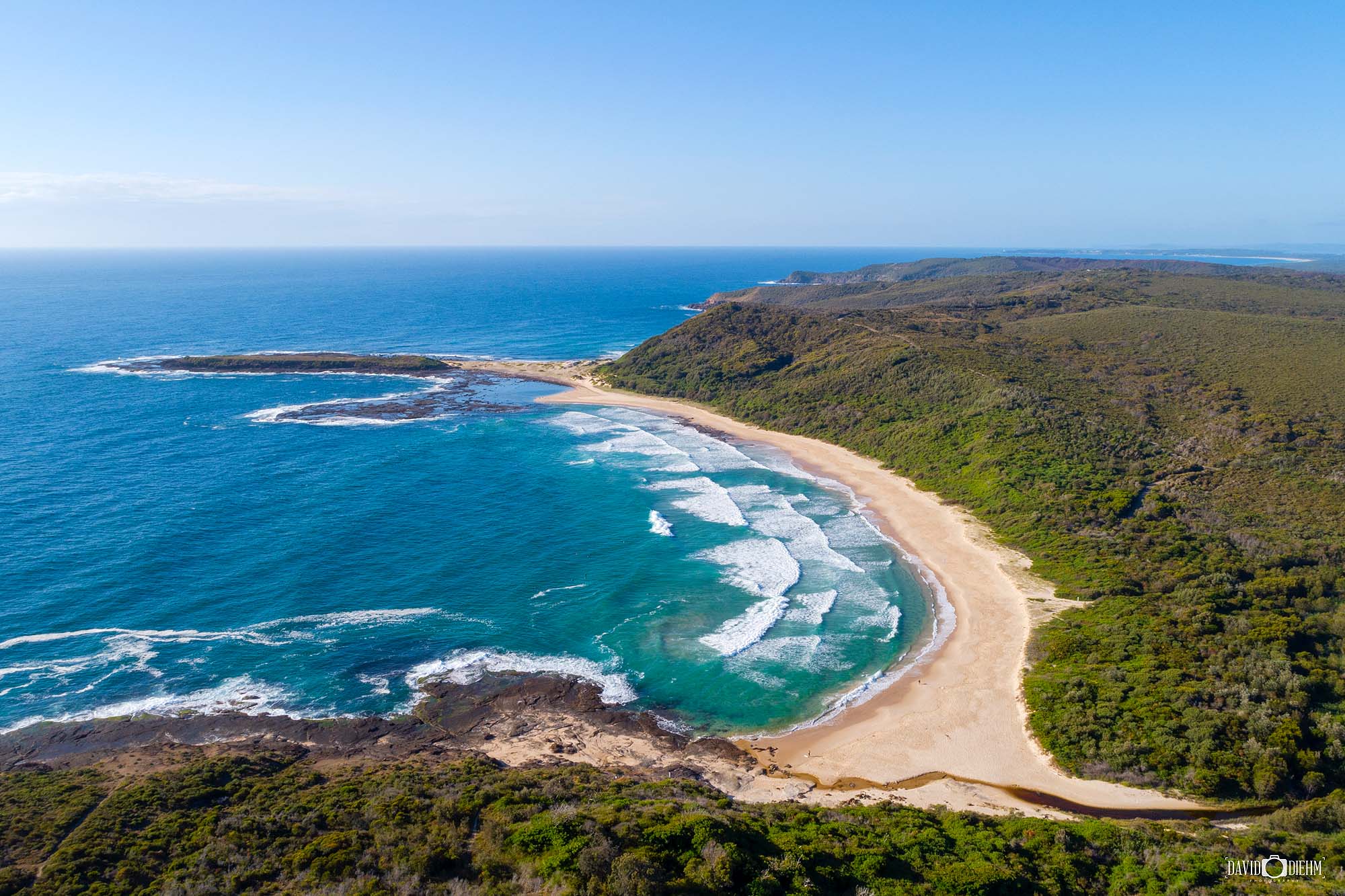 Aerial view of Moonee Beach in Lake Macquarie on a perfect summer morning with soft sunlight and clear coastal water