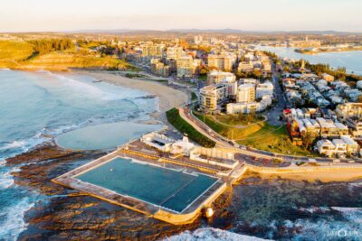Aerial view of Newcastle Ocean Baths at sunrise with perfect morning sunlight over the ocean pool