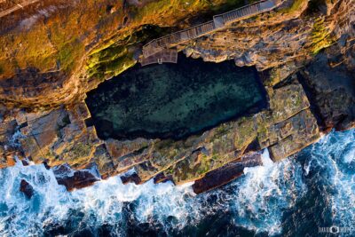 Aerial view of the Bogey Hole in Newcastle at morning sunlight showing the ocean swimming pool carved into rock