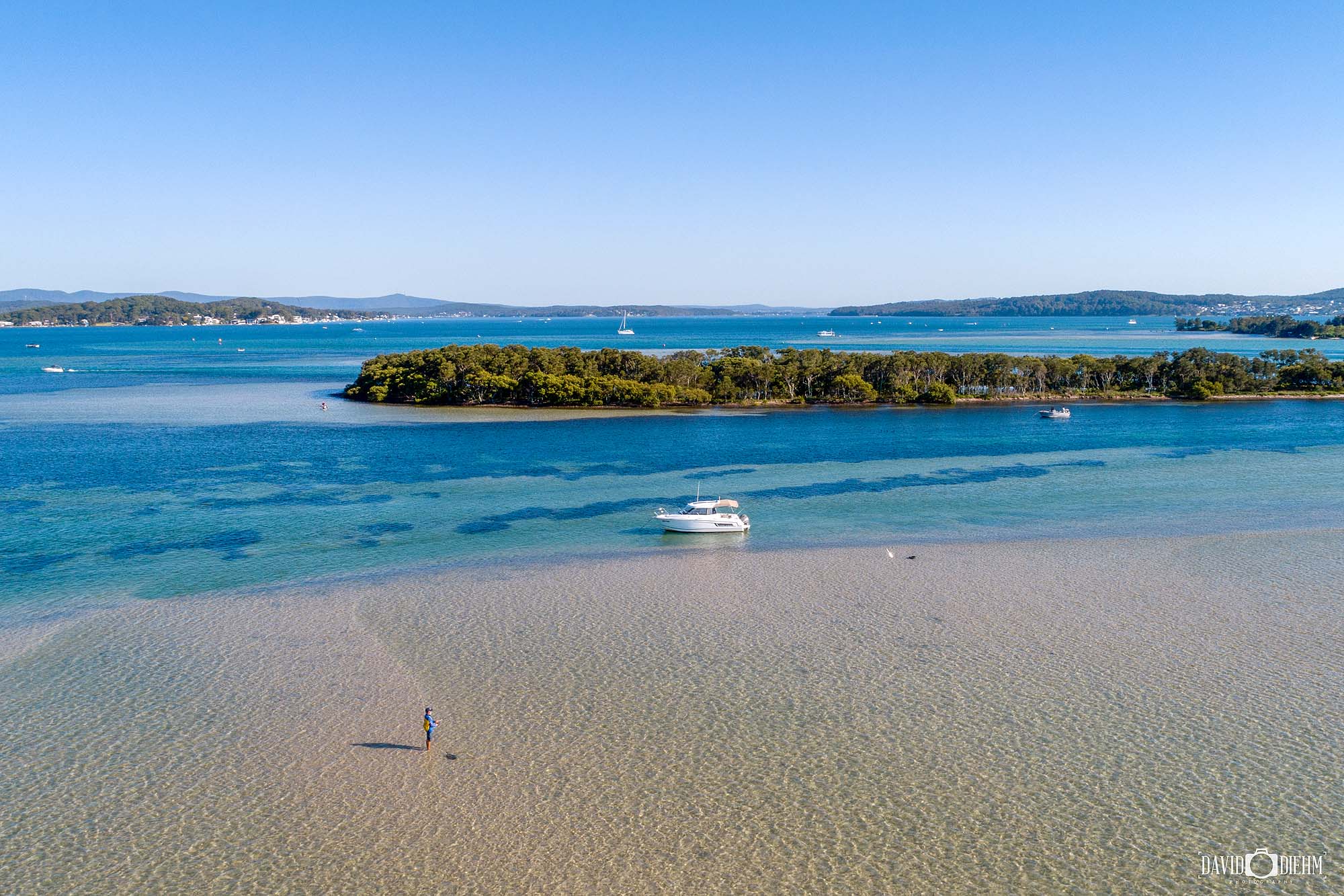 Fishing scene in Swansea Channel, Lake Macquarie showing turquoise water and exposed shoreline at low tide