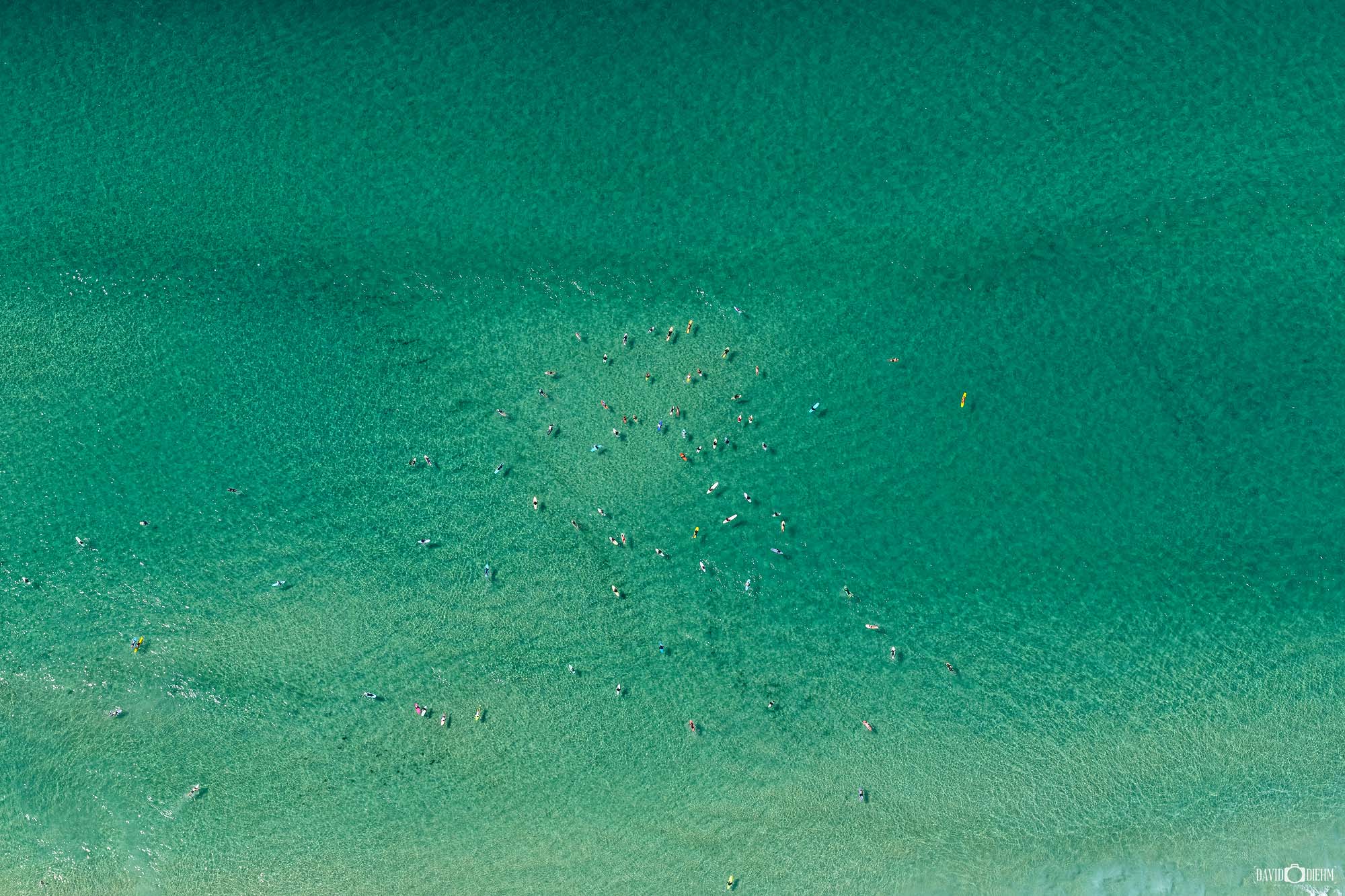 Aerial view of Bondi Beach with surfers in turquoise water on a clear summer day, Sydney NSW