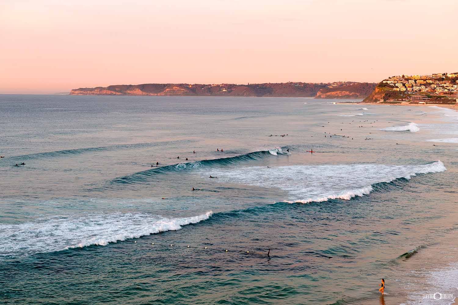 Surfers enjoying clean waves at sunset off Bar Beach in Newcastle.