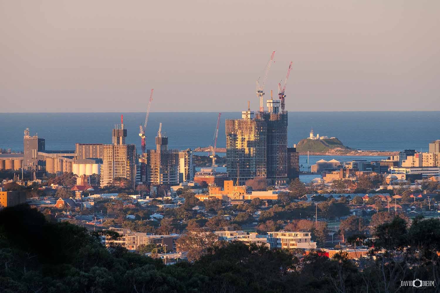 View of the Newcastle skyline from New Lambton Heights Lookout with Nobbys Head Lighthouse in the distance.