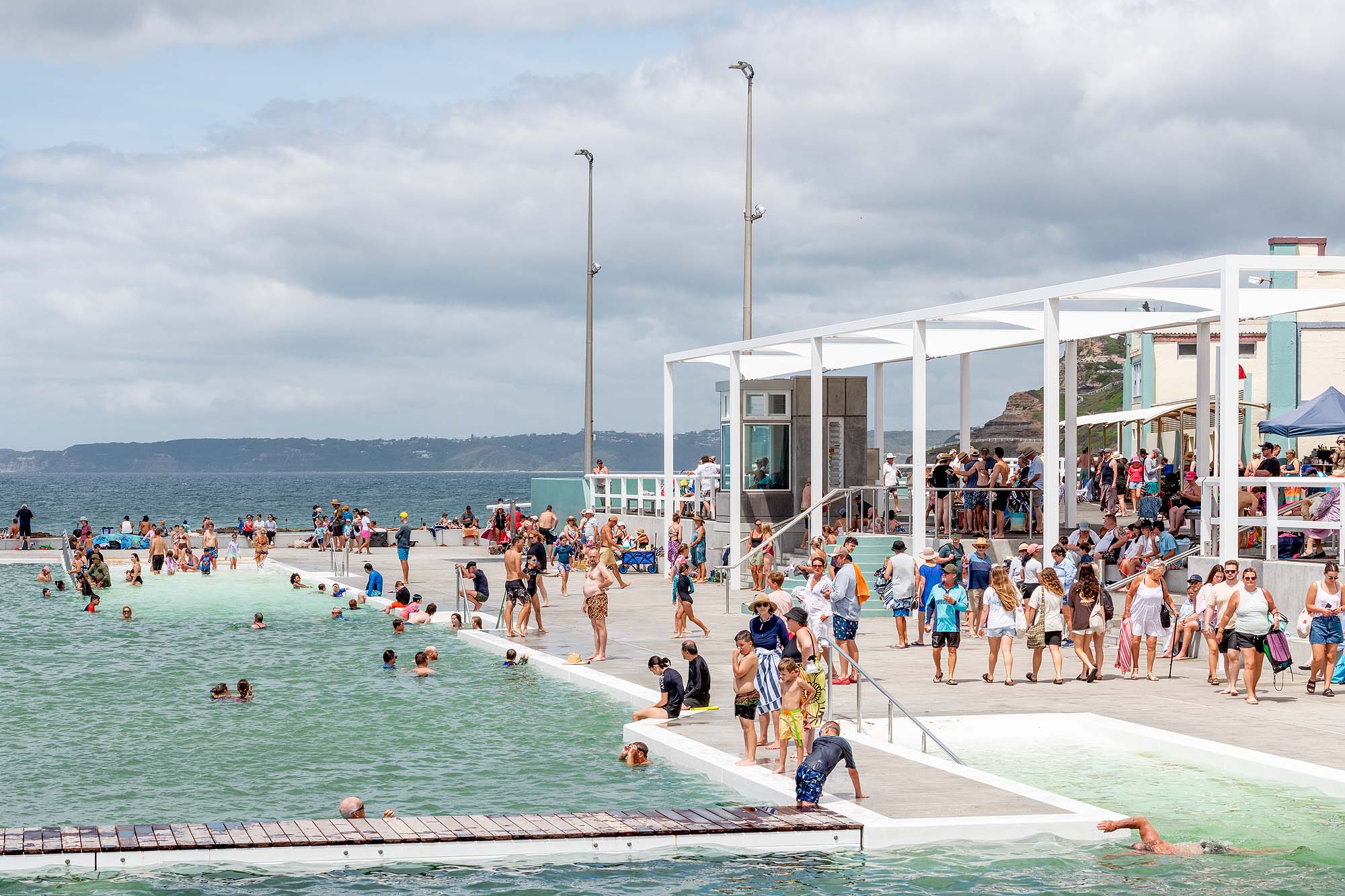Newcastle Ocean Baths on a busy summer day with people enjoying the coastal pool for tourism photography