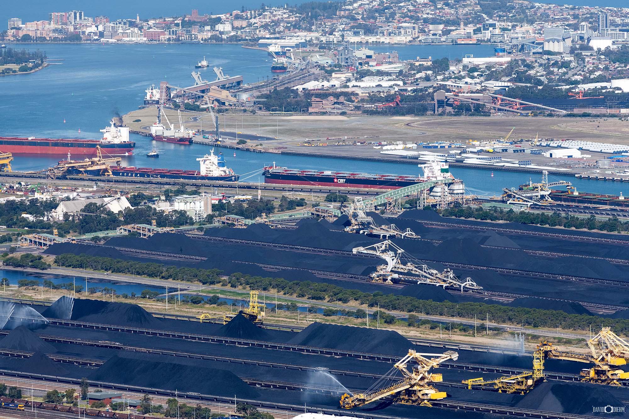 Coal loading operations in Newcastle Harbour berthing channel with bulk carrier ship at port, Australia’s major coal export hub