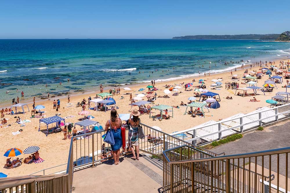 Visitors overlooking Bar Beach Newcastle from the beachfront promenade on a sunny summer day