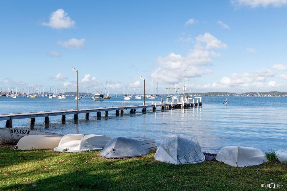 Belmont Baths jetty overlooking calm waters and sailing boats on Lake Macquarie NSW