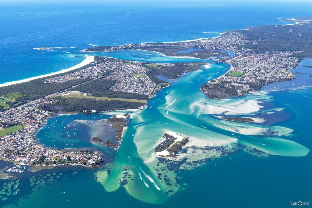 Aerial view of Lake Macquarie showcasing turquoise water, sandy shoreline and Australia's largest coastal saltwater lake in perfect sunlight