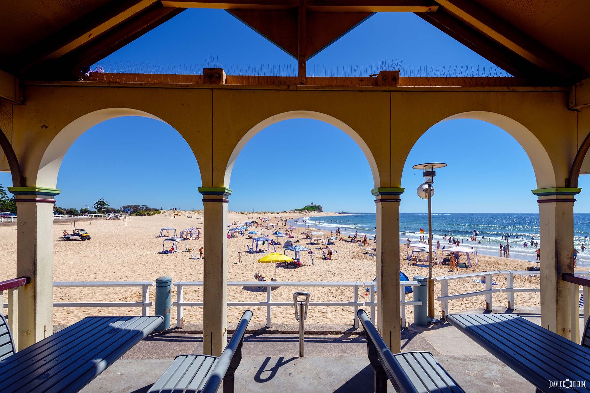 Visitors enjoying Nobbys Beach with views towards Nobbys Lighthouse in Newcastle NSW