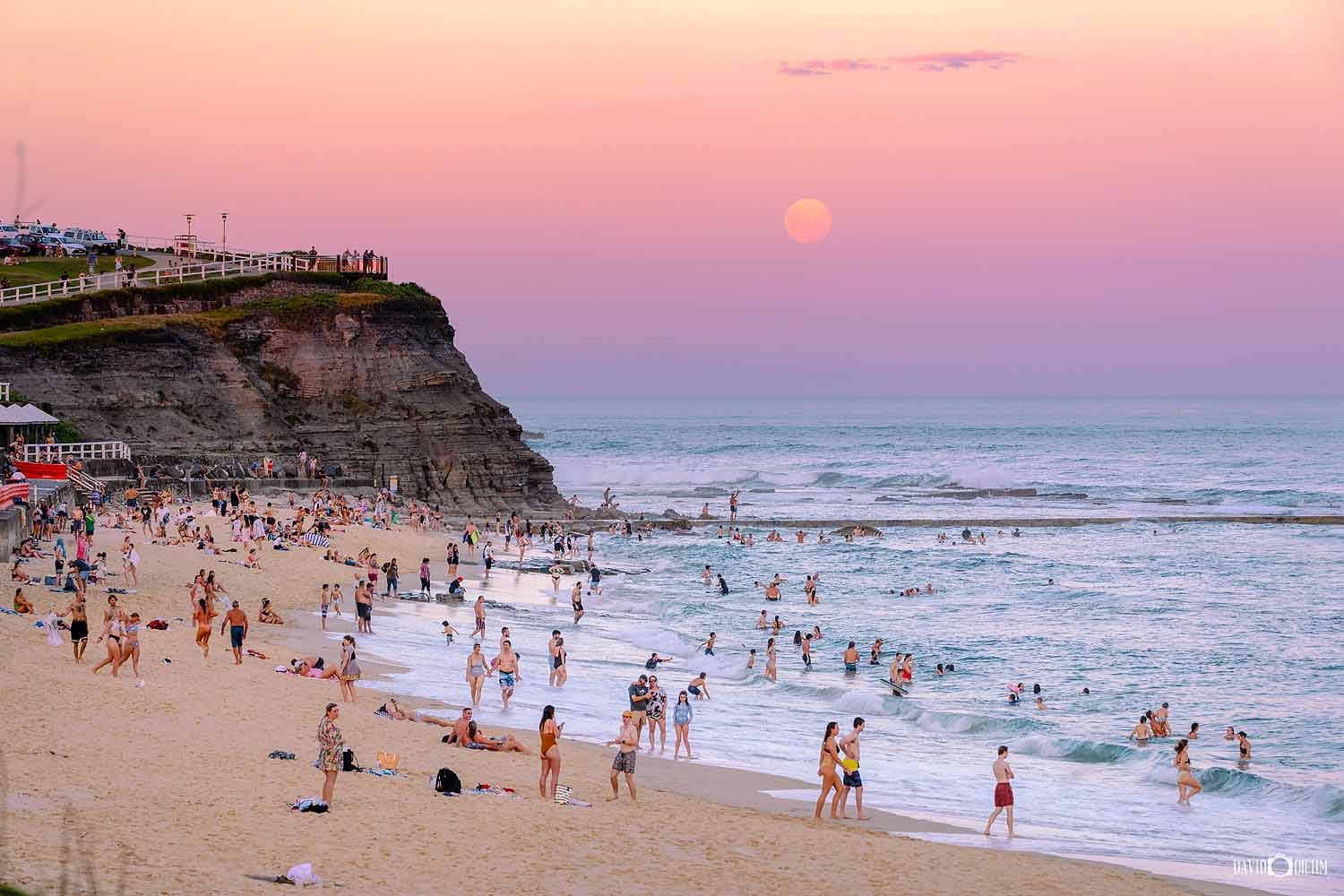 bar-beach-newcastle-sunset.jpg Visitors enjoying Bar Beach at sunset beneath a pastel sky in Newcastle, NSW.