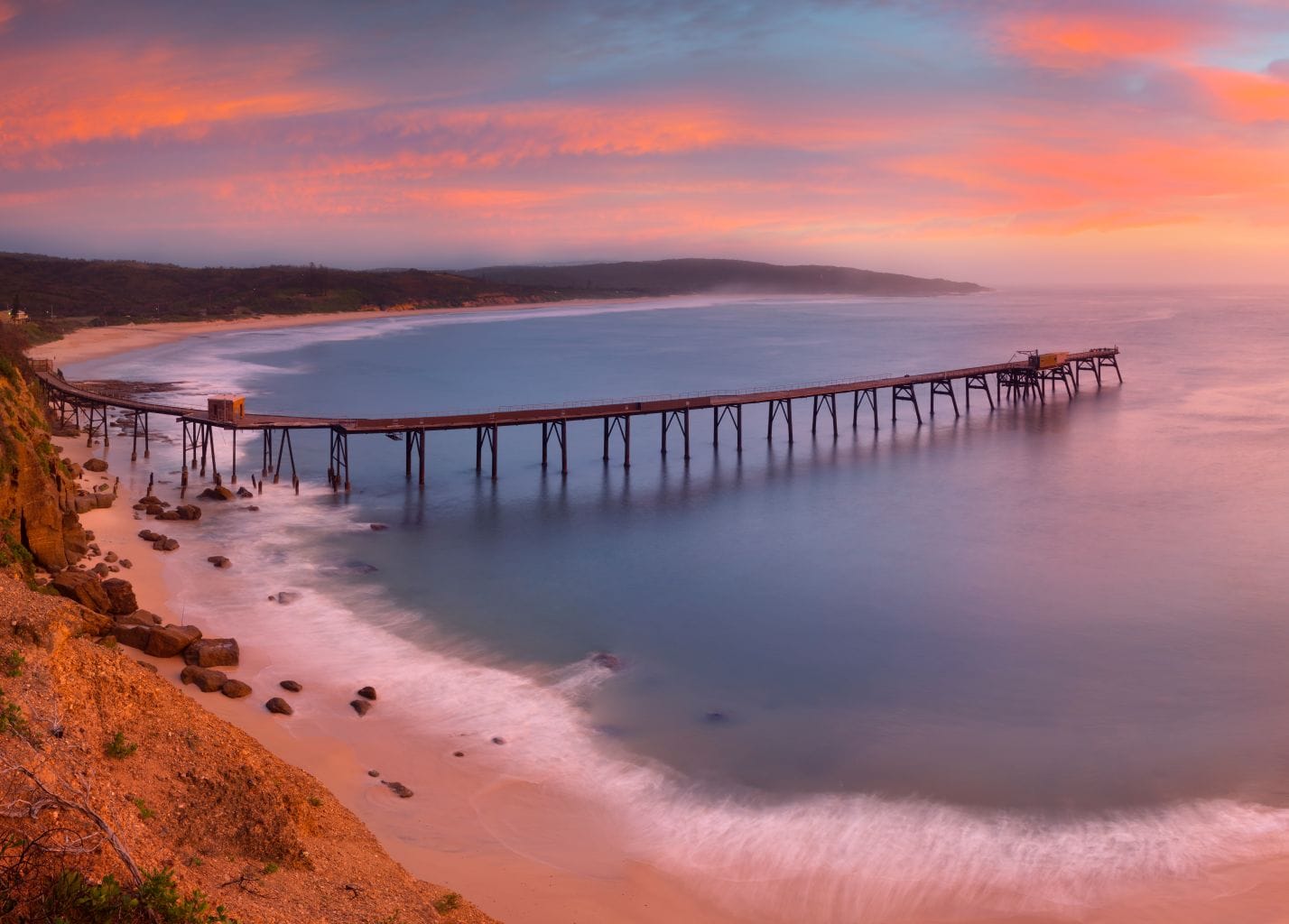Historic Catherine Hill Bay jetty extending into the Pacific Ocean at sunrise in Lake Macquarie NSW