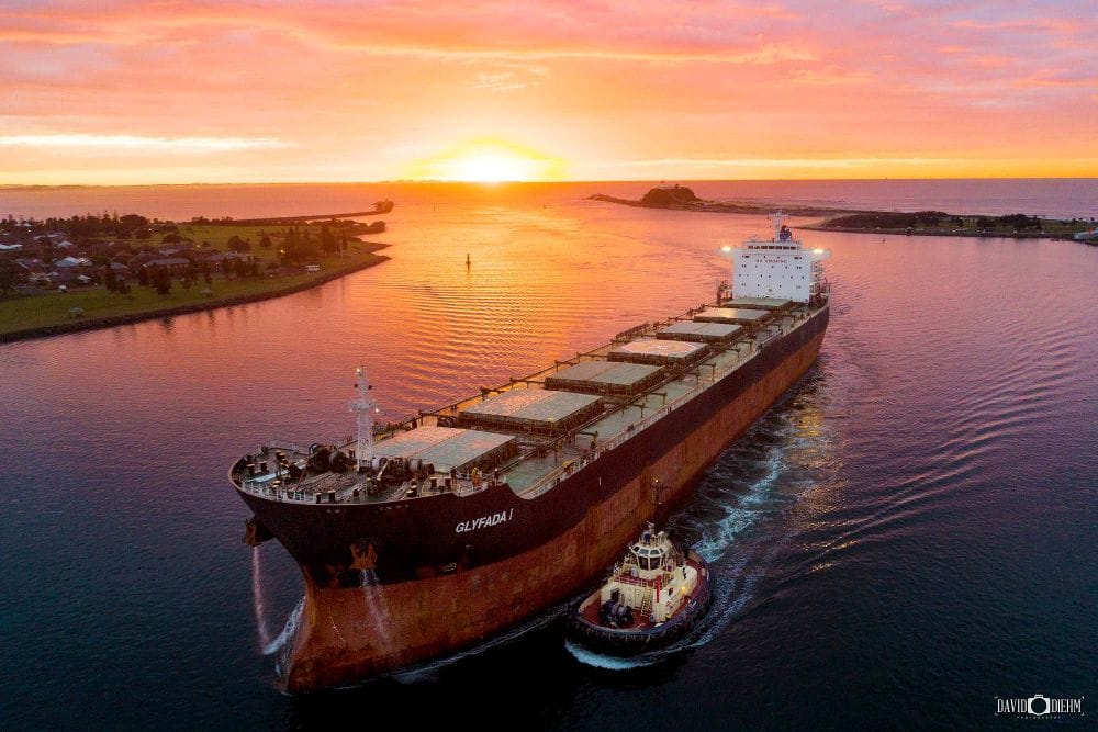 Aerial view of a coal ship entering Newcastle Harbour at sunrise with Nobbys Head in the distance
