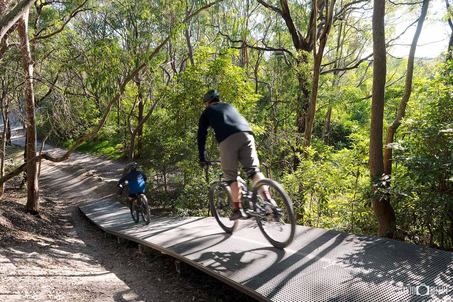 glenrock-boardwalk-mountain-bike-trail.jpg Mountain bikers riding across a boardwalk feature in Glenrock State Conservation Area, Newcastle.