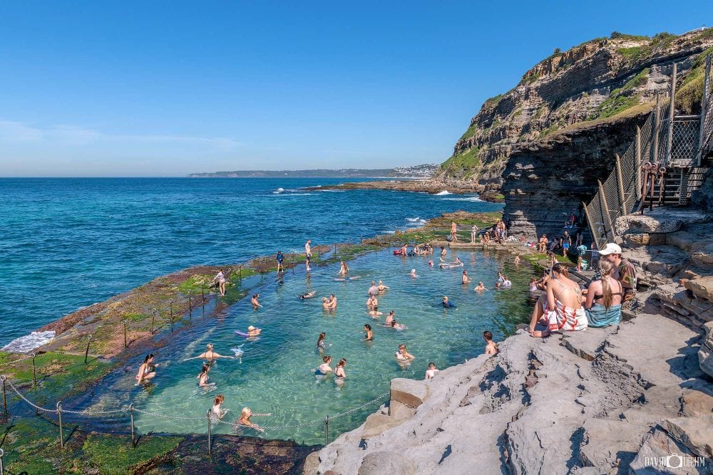 Visitors swimming in the historic Bogey Hole ocean pool beneath King Edward Park Newcastle NSW