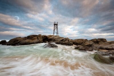 Ocean swell washing over the rocks below the Redhead Shark Tower during high tide at Redhead Beach NSW