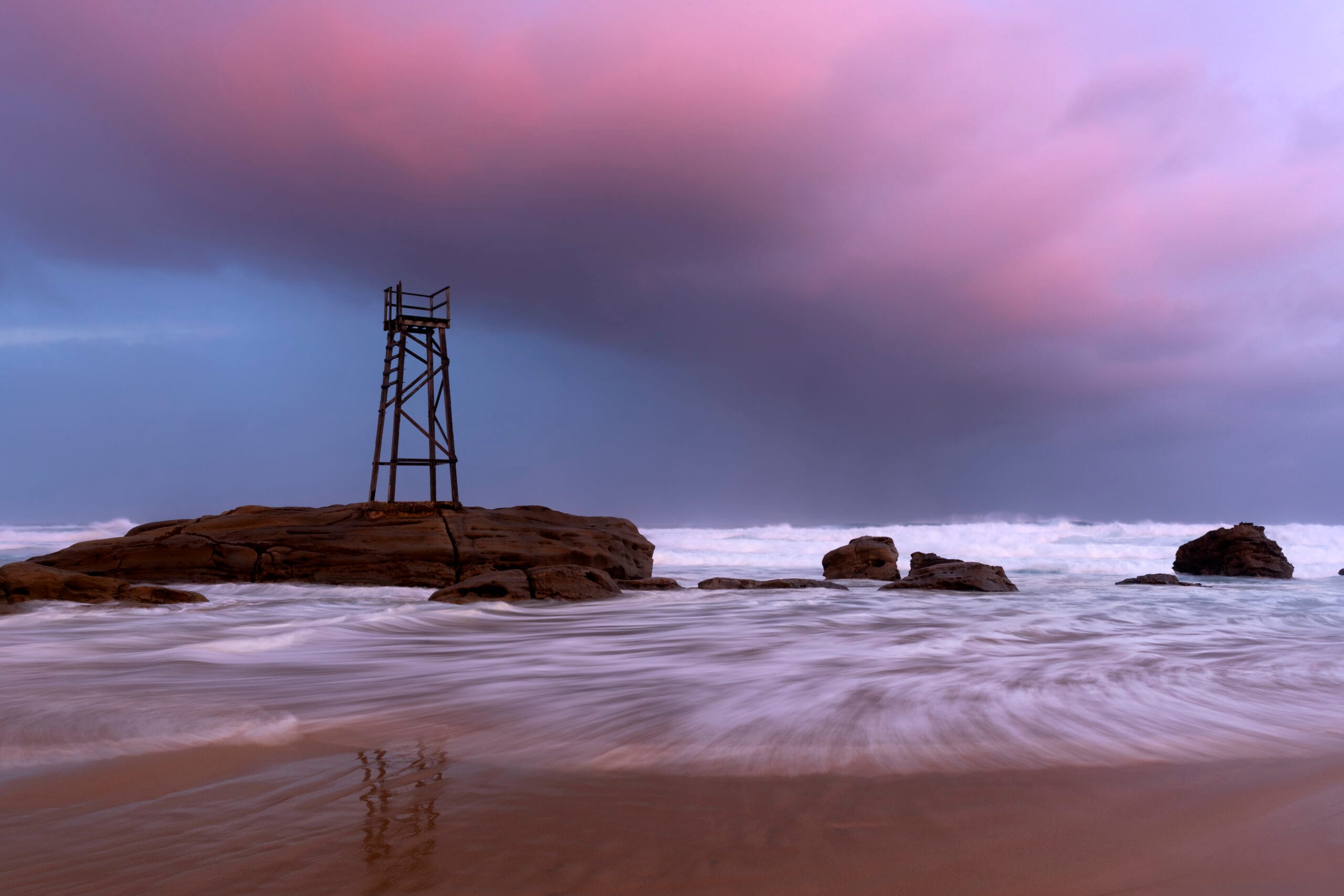 Storm clouds gathering over the Redhead Shark Tower at sunset on Redhead Beach NSW