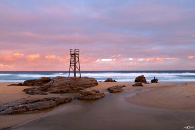 Sunset light illuminating Redhead Beach after rain as clearing skies glow above the coastline