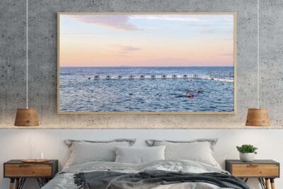 Morning Ritual wall art featuring swimmers at Merewether Ocean Baths in golden morning light displayed in a modern home.