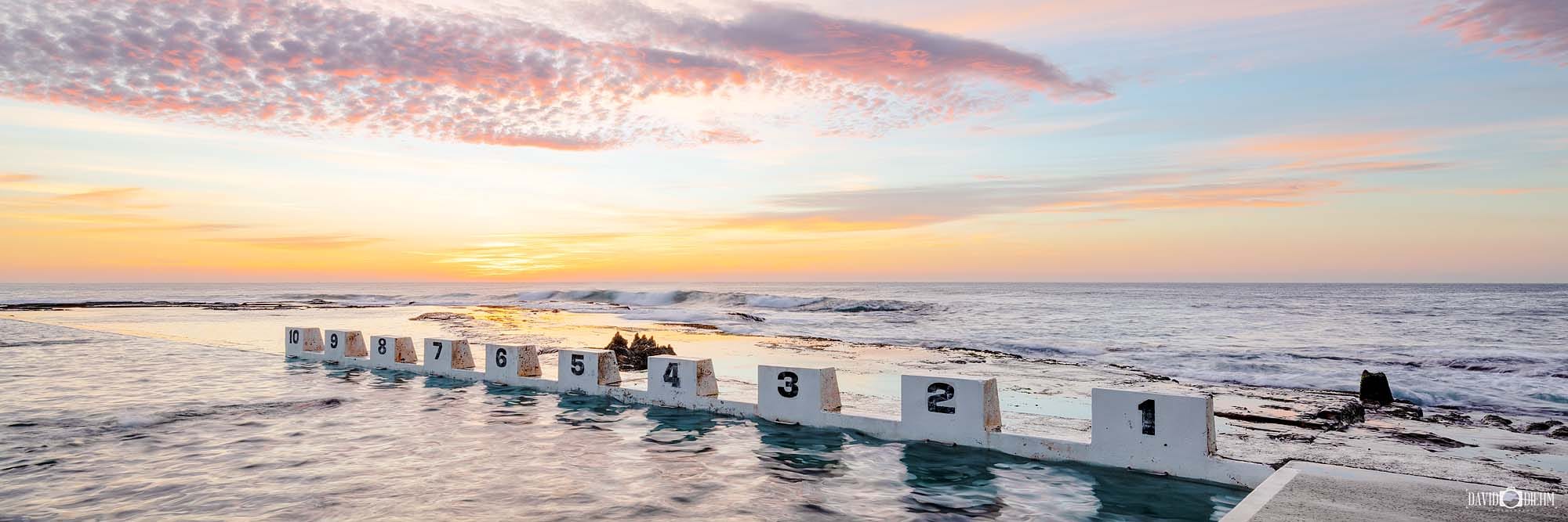 Sunrise illuminating the iconic concrete blocks at Merewether Ocean Baths in Newcastle NSW