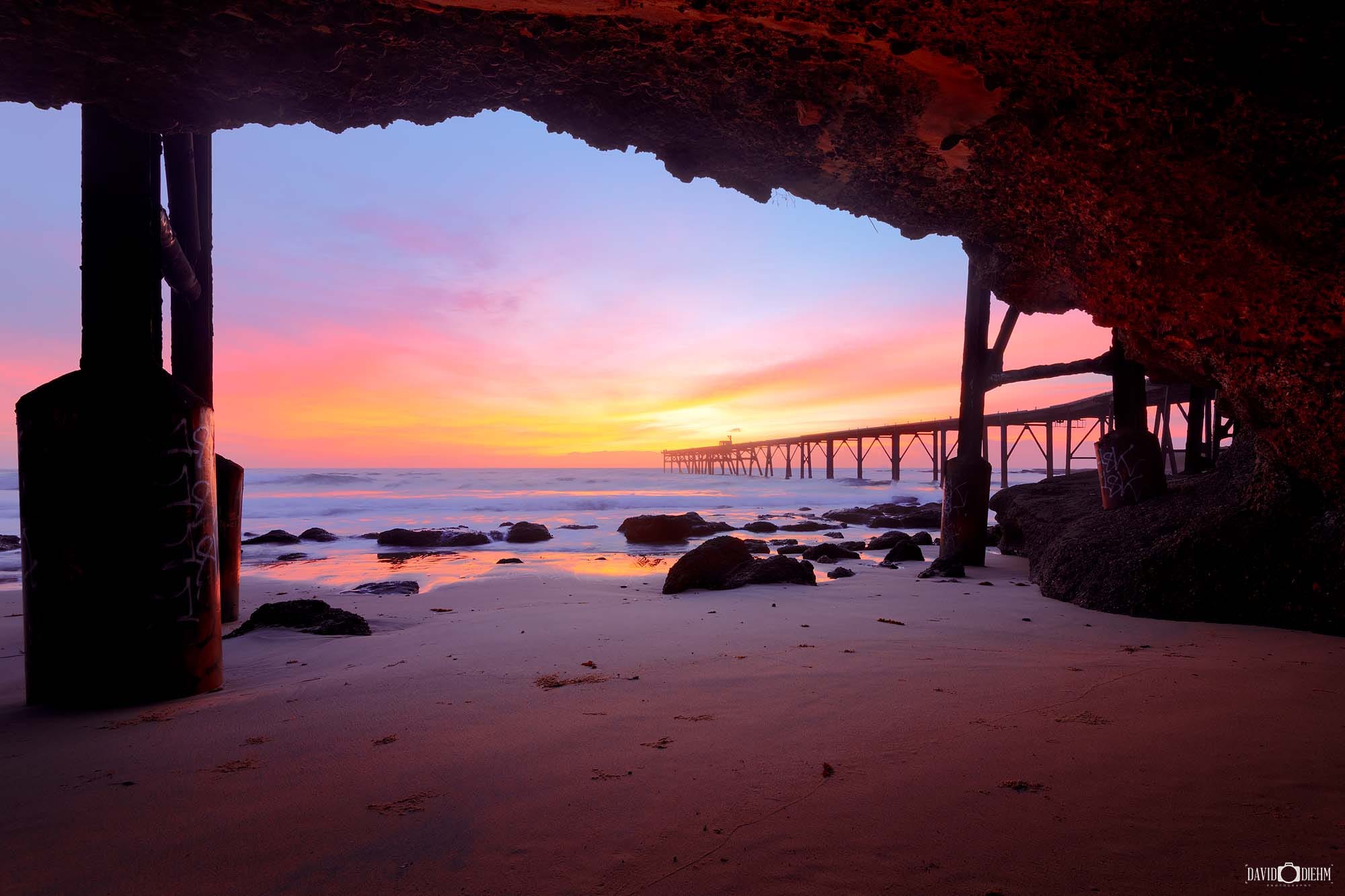 Historic Catherine Hill Bay jetty viewed through a coastal cave on the Lake Macquarie coastline