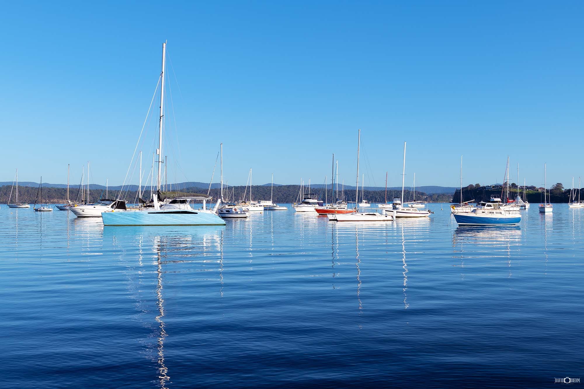 Blue Reflections wall art featuring boats mirrored in calm waters beneath blue skies on Lake Macquarie