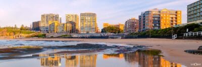 Wide panoramic view of sunrise at Newcastle Beach with vibrant reflections stretching across the beach