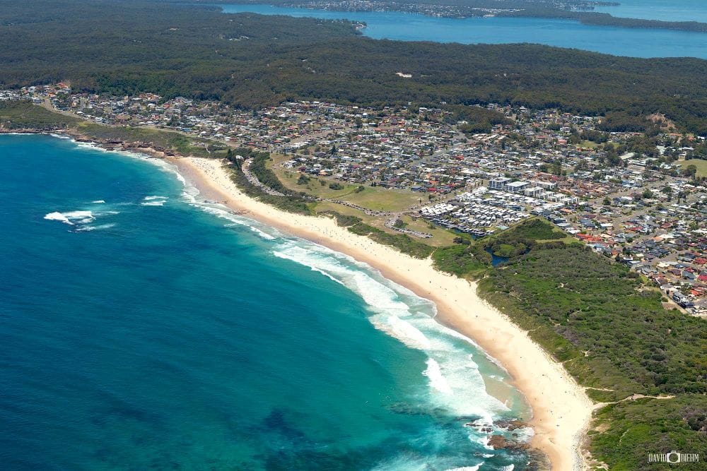 Aerial view of Hams Beach at Swansea Heads showing golden sand, turquoise ocean, coastal bushland and one of Lake Macquarie's popular off-leash dog-friendly beaches.