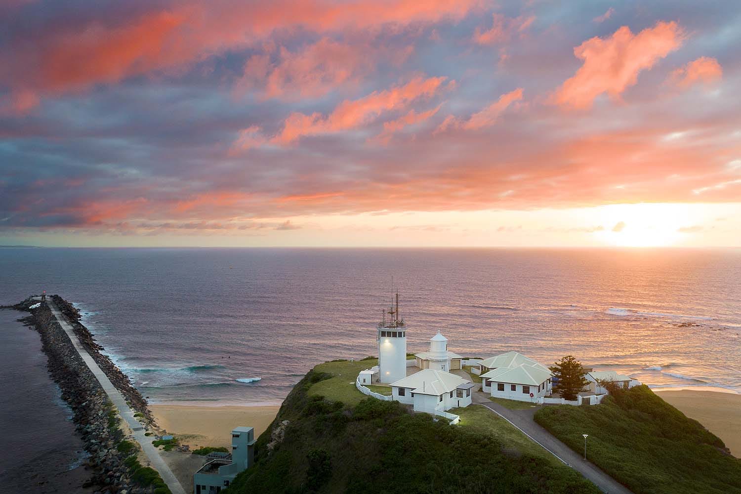 Sunrise over Nobbys Lighthouse and Nobbys Headland overlooking the Pacific Ocean in Newcastle NSW.