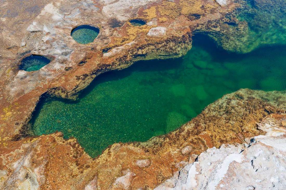 Aerial view of the crystal-clear rock pools near Catherine Hill Bay, showcasing turquoise water carved into the coastal rock platform along one of Lake Macquarie's most scenic coastal walks.
