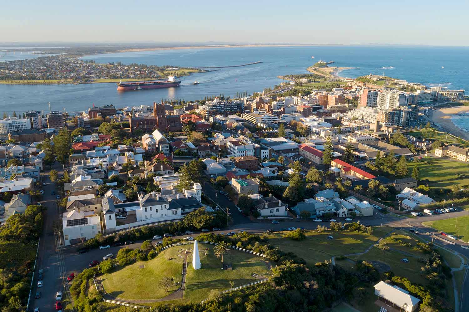 Aerial view of The Obelisk overlooking Newcastle Harbour, Nobbys Headland and the city skyline in NSW.
