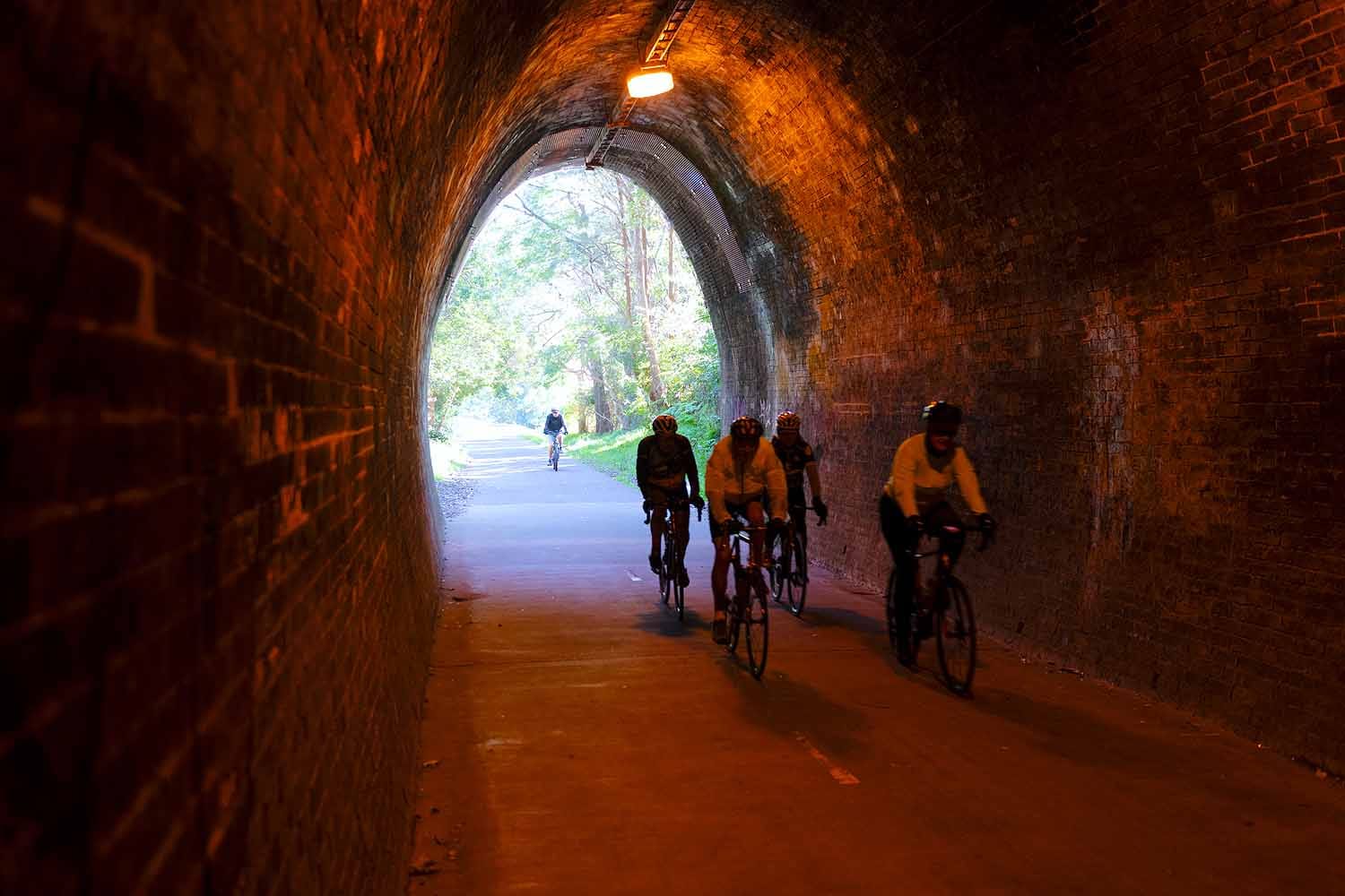 Cyclists riding through the heritage Fernleigh Track Tunnel between Newcastle and Lake Macquarie.