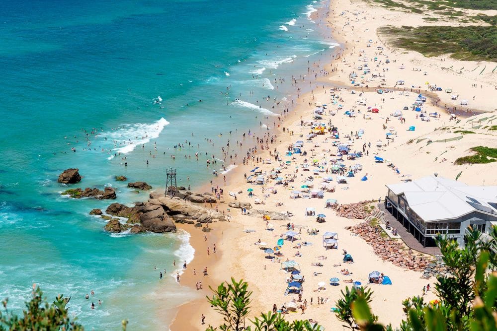 Summer crowds enjoying Redhead Beach in Lake Macquarie with surf club and patrolled swimming area