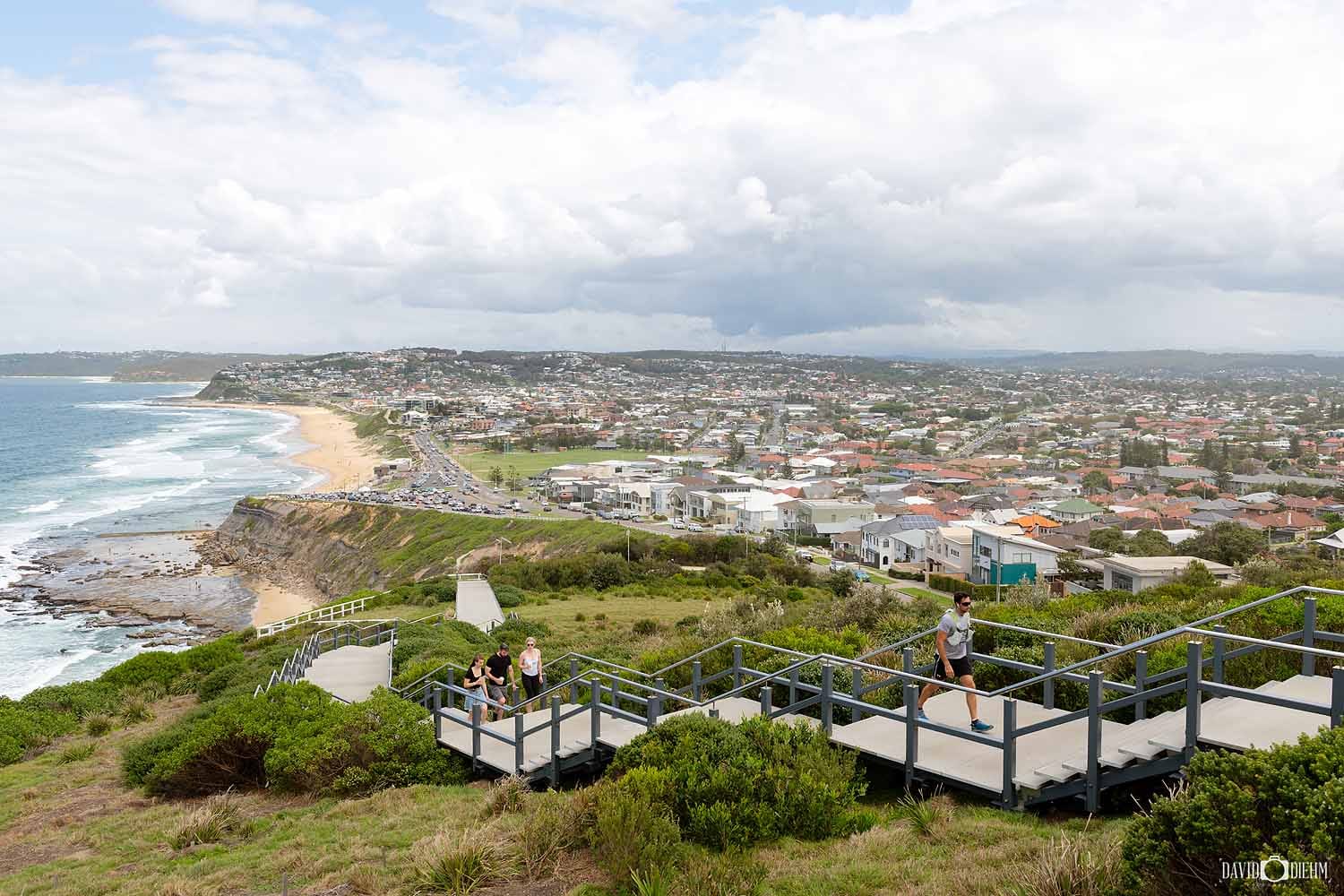 Visitors walking along the ANZAC Memorial Walk overlooking Bar Beach and Newcastle, NSW.
