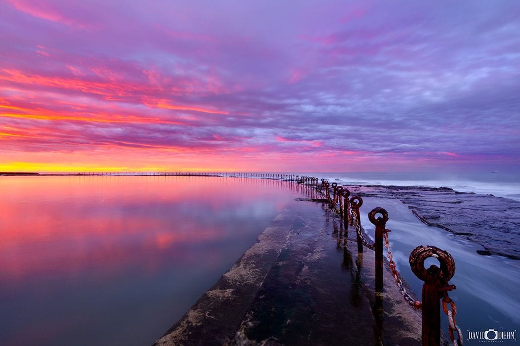 canoe-pool-sunrise-newcastle.jpg Sunrise colours reflecting across the calm waters of Canoe Pool at Newcastle Ocean Baths.