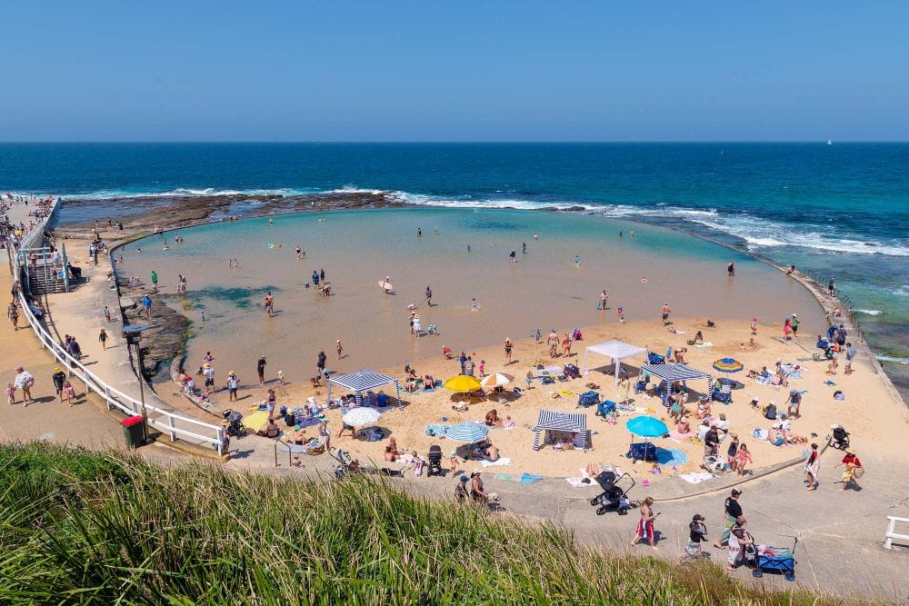 canoe-pool-newcastle-summer-swimming.jpg Families enjoying the shallow waters of Canoe Pool beside Newcastle Ocean Baths on a summer day.