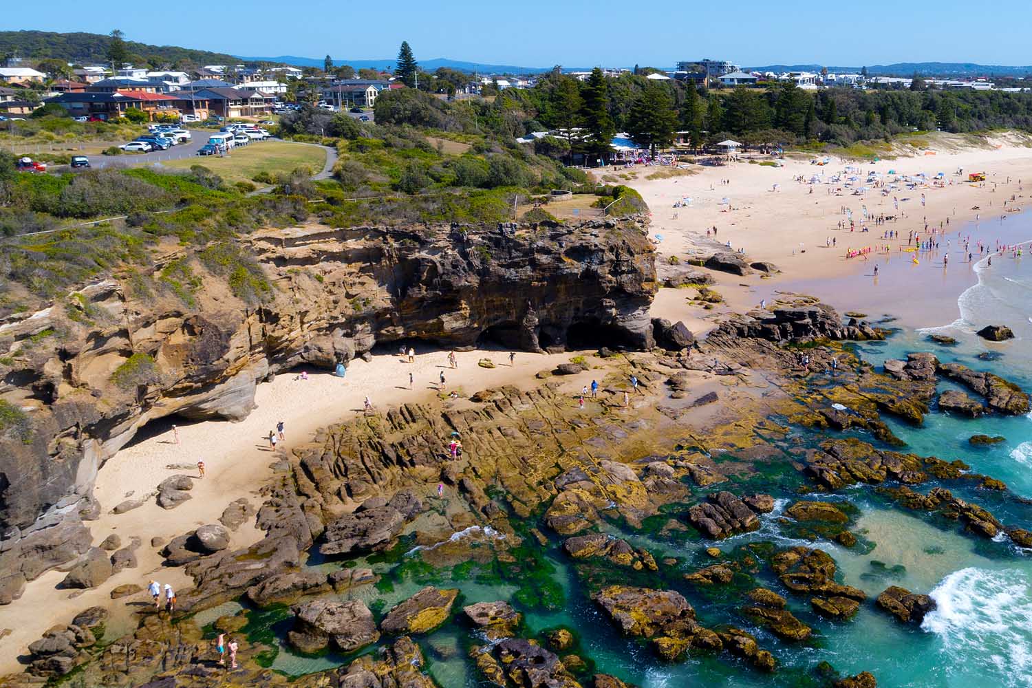 Aerial view of the sea caves at Caves Beach, Lake Macquarie, showcasing sandstone cliffs, rock pools, turquoise water and one of the region's most iconic coastal attractions.