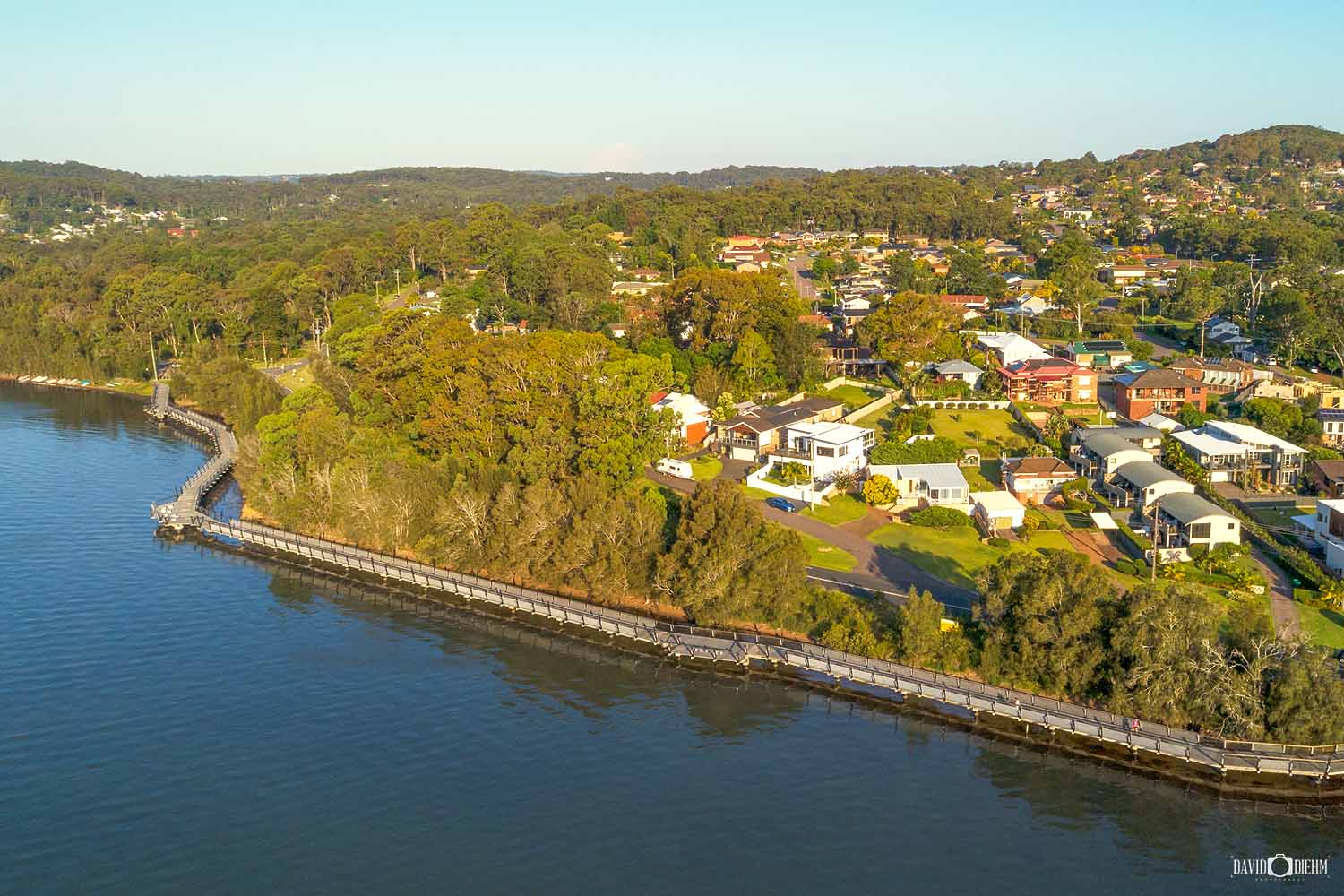 The Eleebana Red Bluff Boardwalk overlooking Lake Macquarie with paddleboarders on the water.